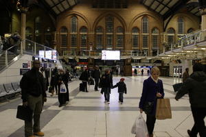 afrocarribean, artificial lighting, crowd, display, England, eye level view, family, girl, indoor lighting, interior, London, man, people, station, The United Kingdom, winter