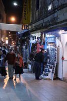 arabic, artificial lighting, autumn, clothing, crowd, Essaouira, eye level view, market, Morocco, night, people, souvenir, stall, tourist