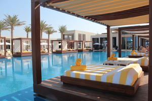 bed, building, building, day, direct sunlight, Dubai, Dubayy, eye level view, hotel, hotel, natural light, palm, plant, pool, sunbed, sunlight, sunny, sunshine, The United Arab Emirates, tree